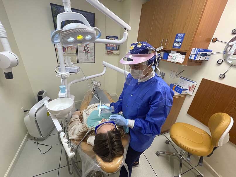 Dental hygienist performing deep teeth cleaning and scaling and root planing for a patient at Atlas Park Dental in Glendale, NY