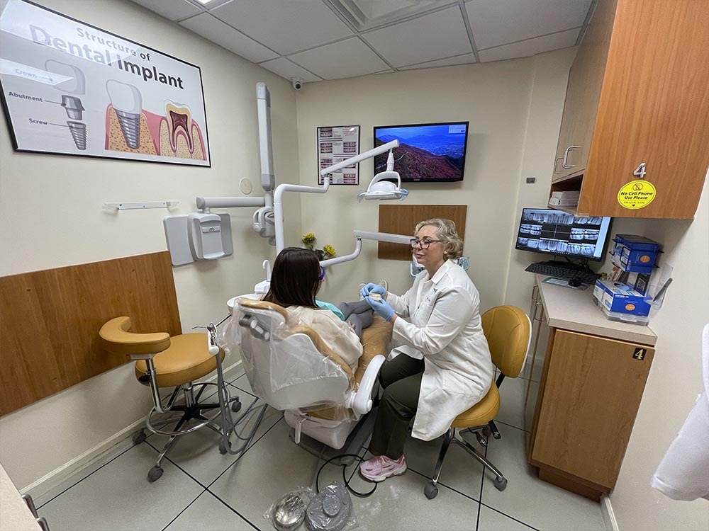 Dentist consulting a patient about denture implants at Atlas Park Dental in Glendale, Queens