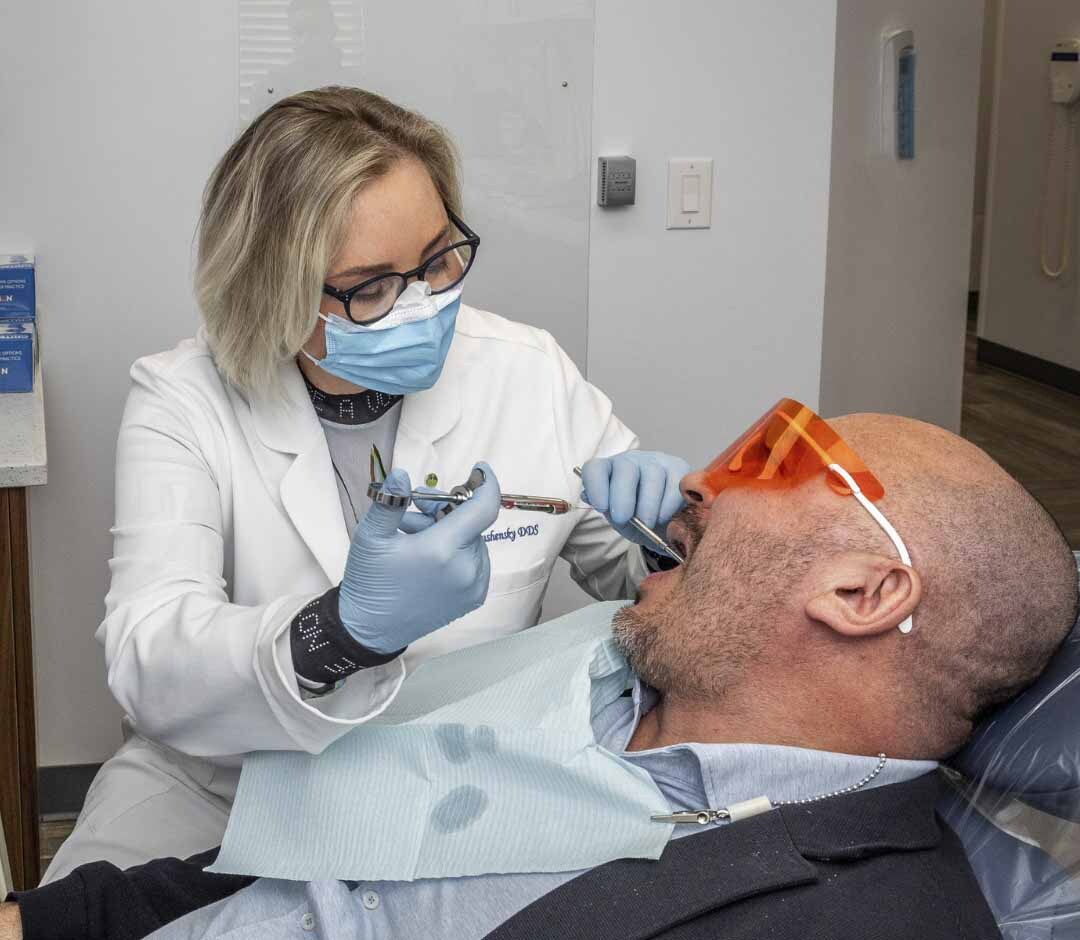 Dentist examining a patient for emergency dental care at Atlas Park Dental in Glendale NY